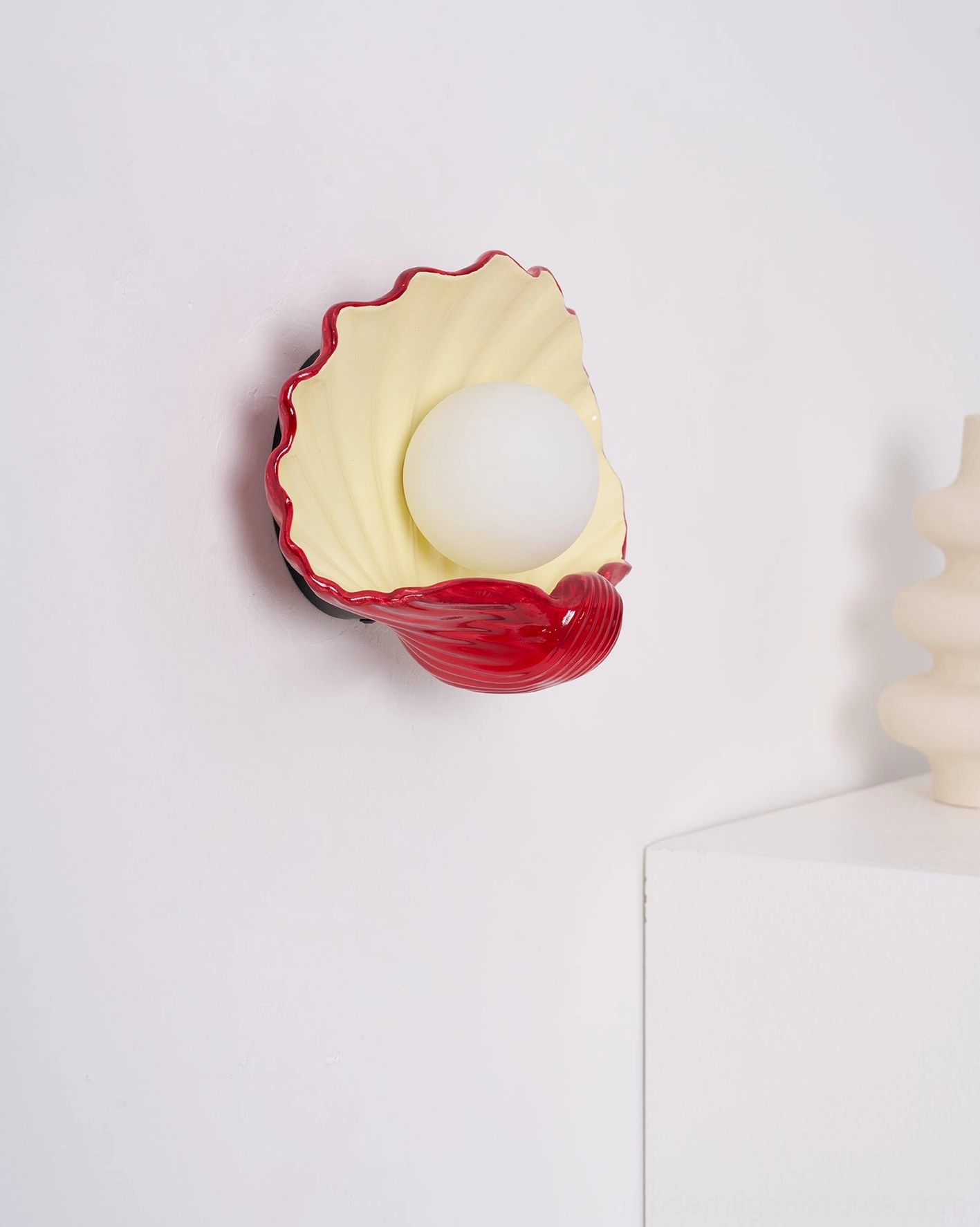 Scallop shell wall sconce mounted in bedroom accent wall, warm ceramic lighting, coastal interior design fixture