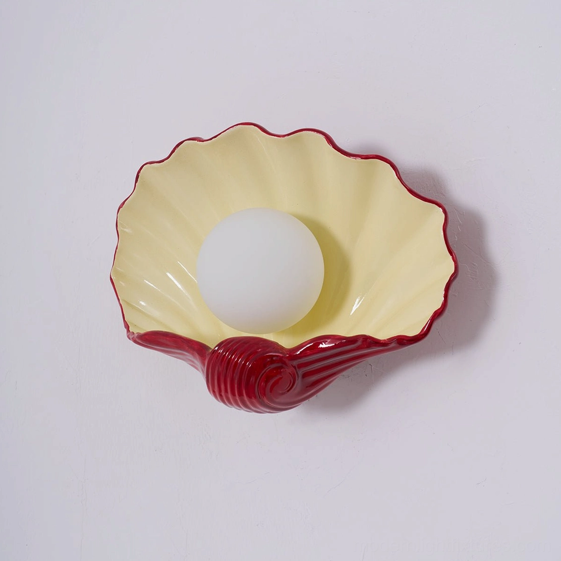 Scallop shell wall sconce product detail, rounded ceramic form with central bulb, artistic lighting component view