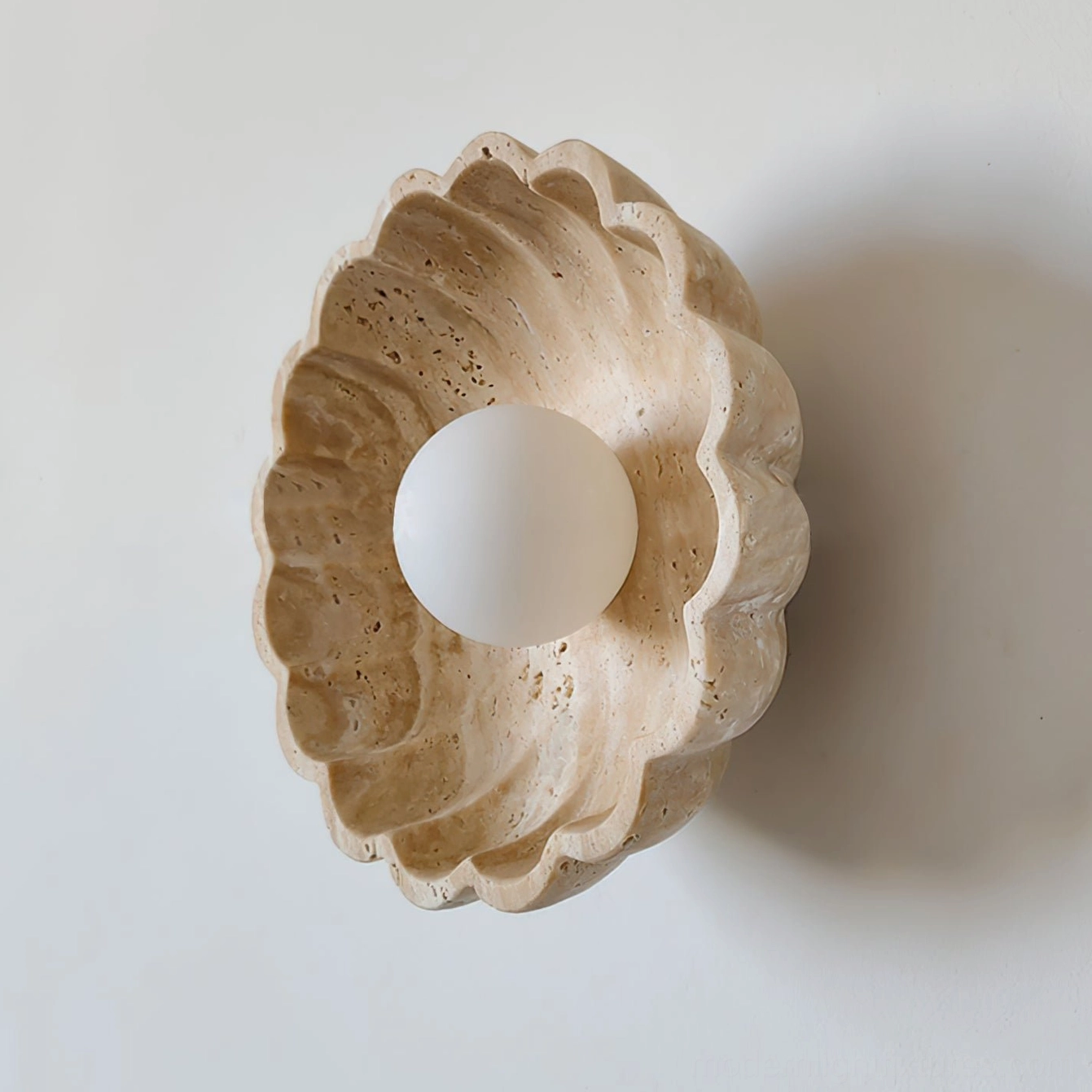 Scallop wall sconce oblique angle showing deep carved scalloped texture and central frosted bulb