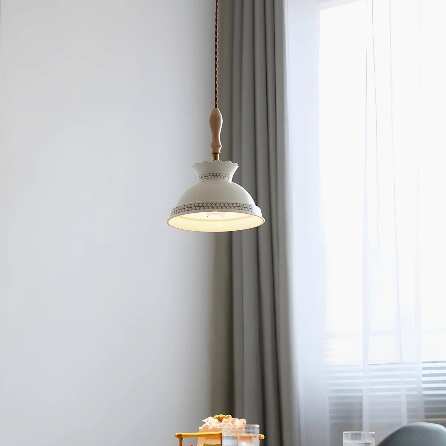 Scalloped ceramic pendant fixture with brass and wood accents in dining corner with sheer curtains