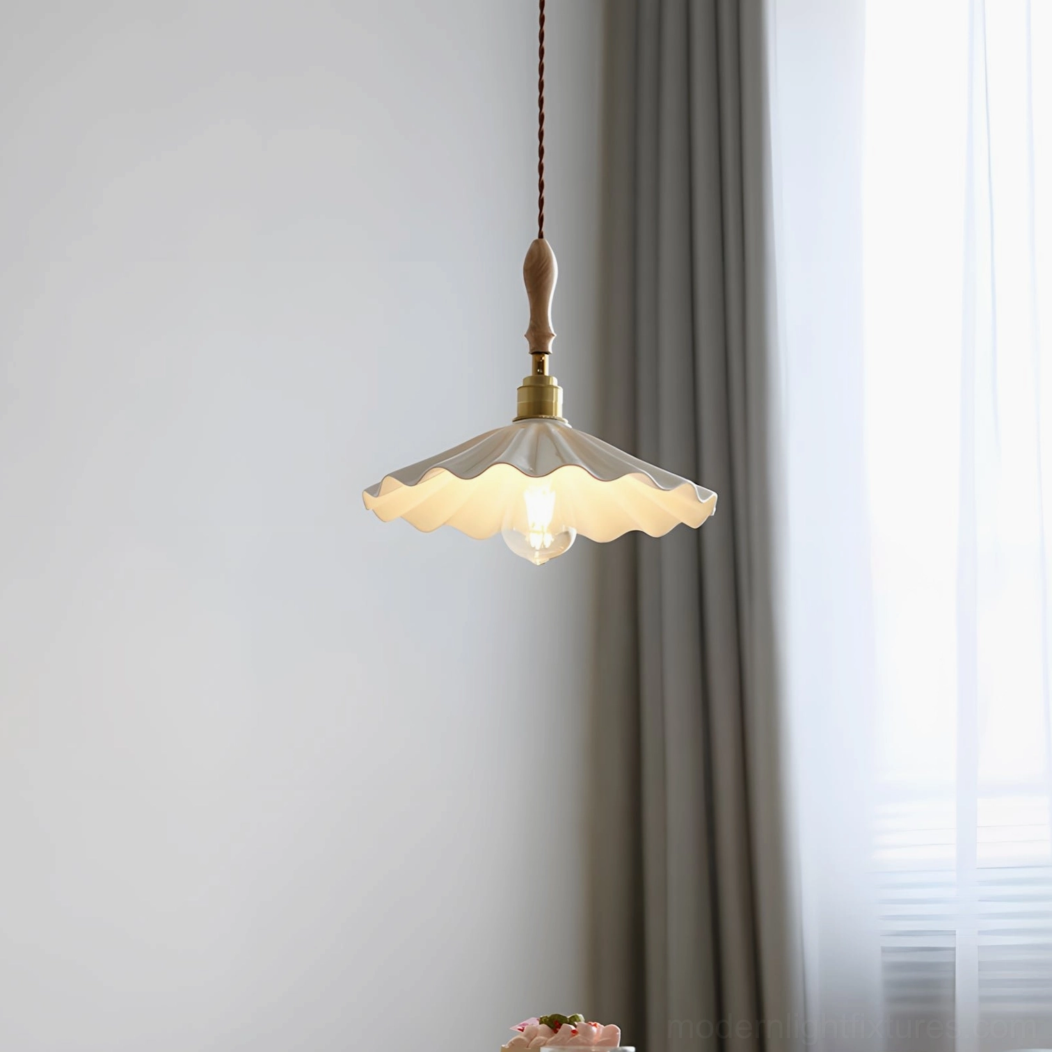 Scalloped edge ceramic pendant lamp casting warm ambient glow above dining table setting