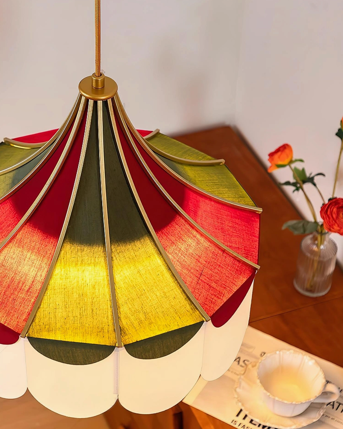 Close-up of red green and cream fabric panels with gold trim on modern scalloped pendant light over dining table