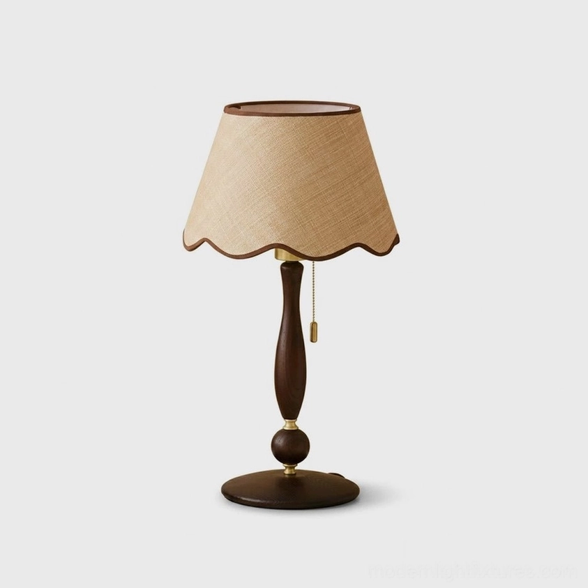 Scalloped linen table lamp with cream fabric shade, walnut-trimmed wavy hem, and dark walnut turned wood spindle with brass ring accent - front studio view