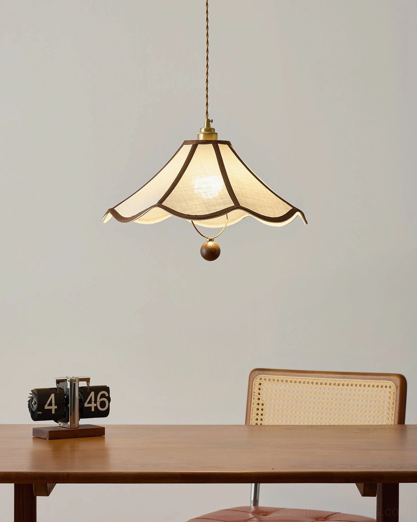 Vintage scalloped pendant light hanging above small dining nook with wooden table and woven chair
