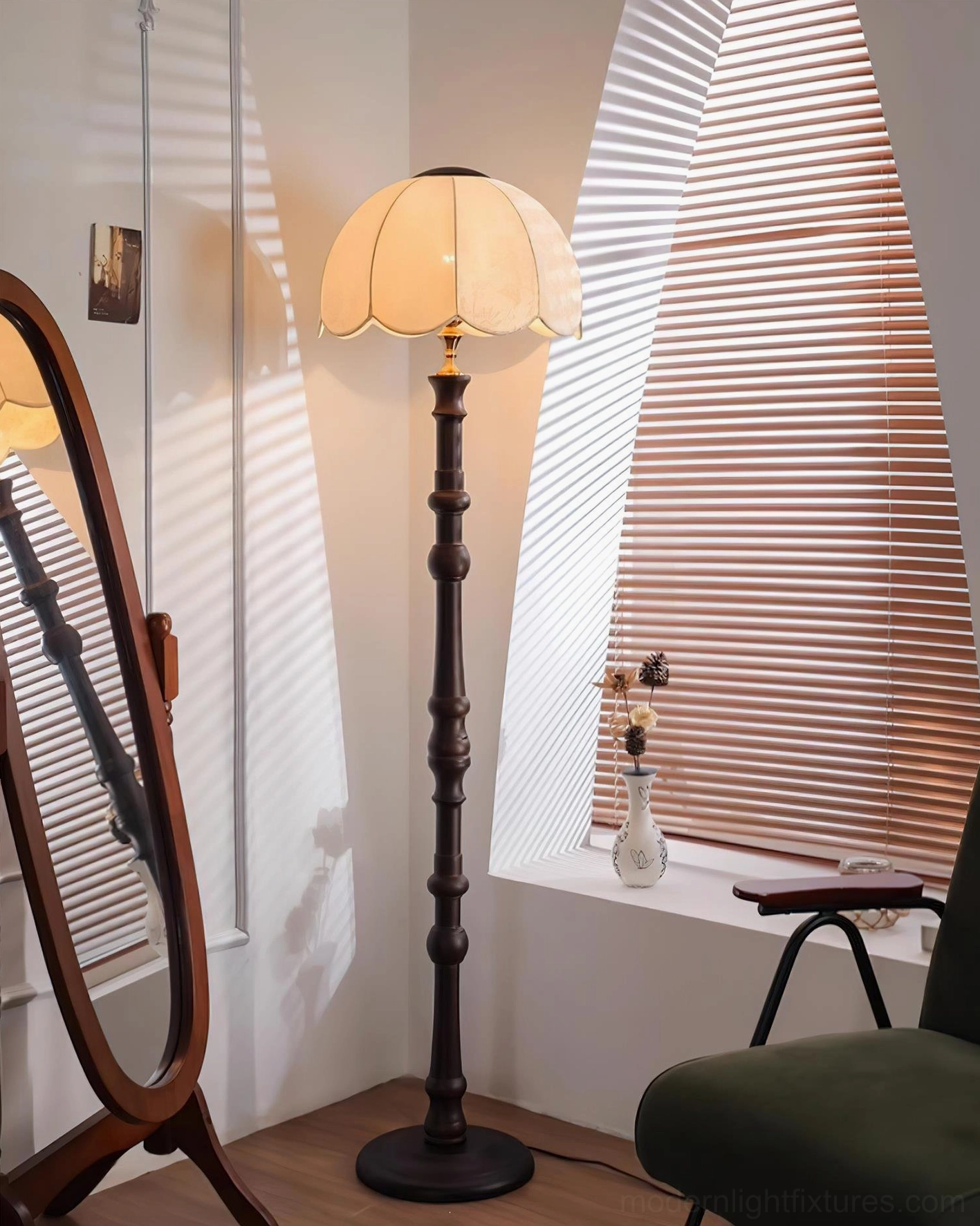 Scalloped vintage floor lamp with dark carved pole and fabric shade in residential corner with arched window blinds and lounge chair