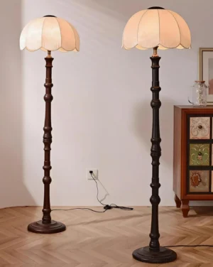 Two matching scalloped vintage floor lamps with dark stained carved poles and warm beige fabric shades in herringbone wood flooring hallway