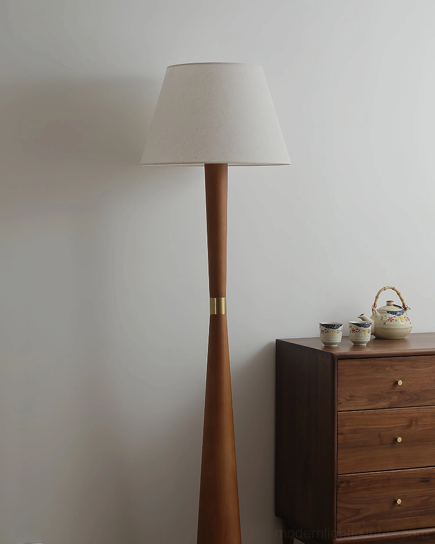 Mid-century modern wooden floor lamp with brass accent ring in bright fabric shade, living room setting