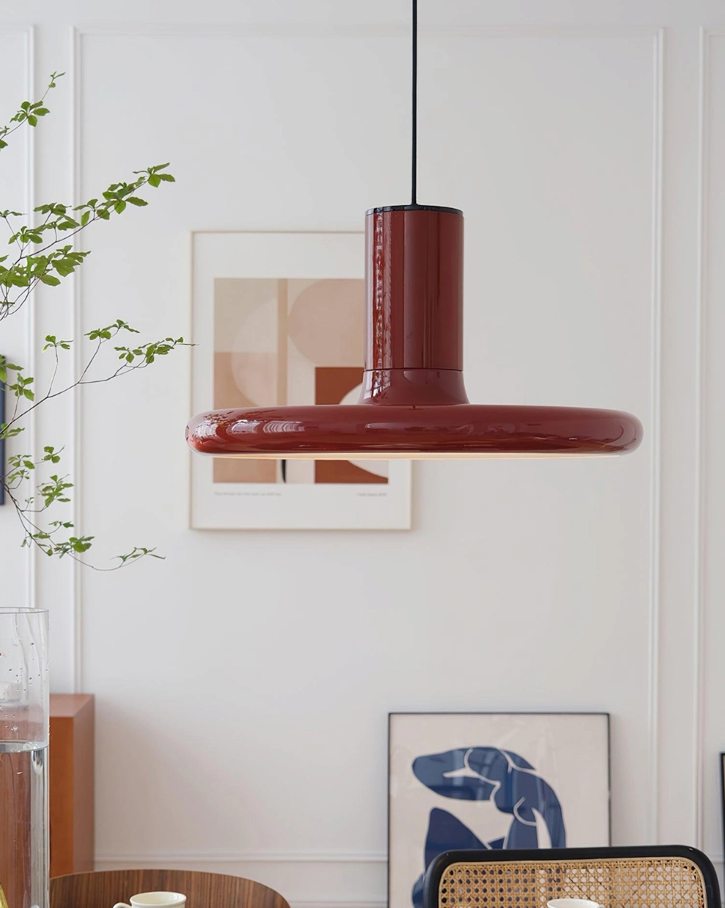 Red glossy disc pendant lamp cozy living space with artwork and green plants
