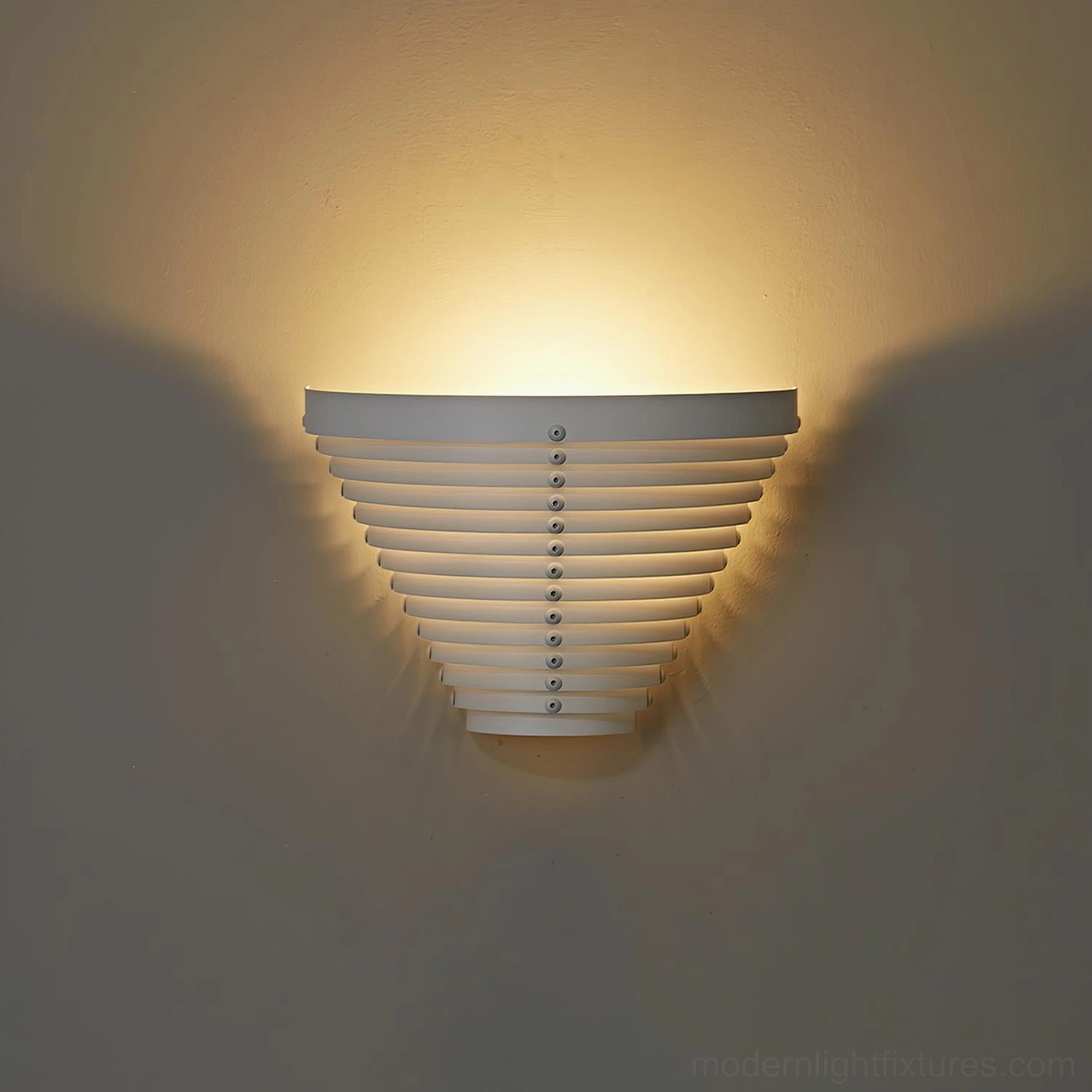Minimalist white metal wall lamp mounted indoors with soft warm upward ambient lighting