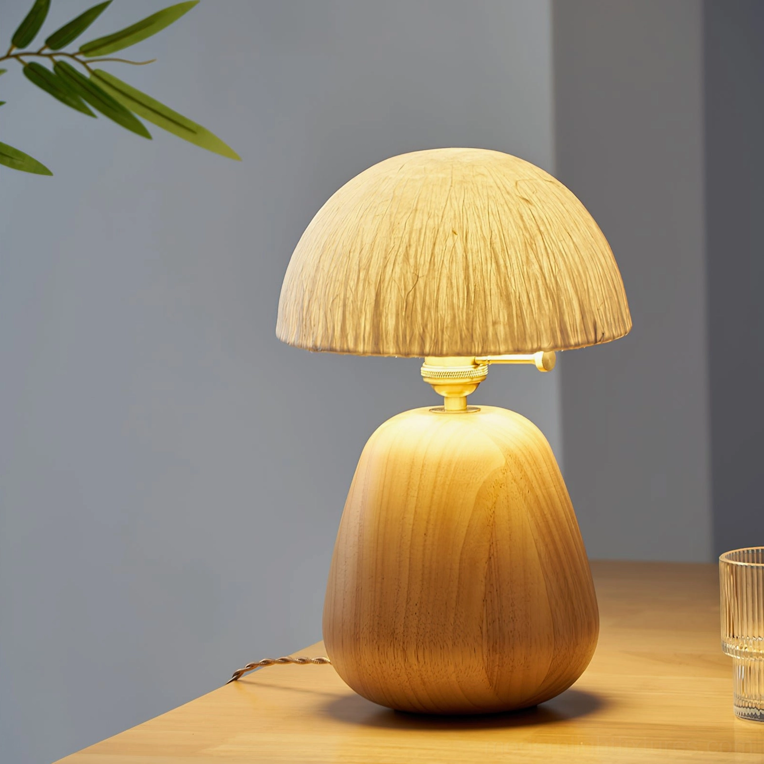 Single oak wood table lamp casting warm ambient light on dining table with neutral grey wall backdrop