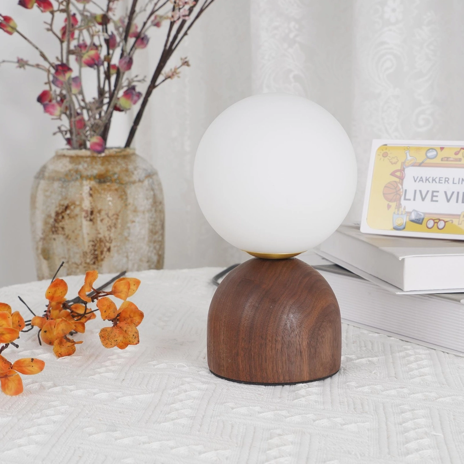 Scandinavian wood table lamp three-quarter view with polka dot cushion background and stacked books
