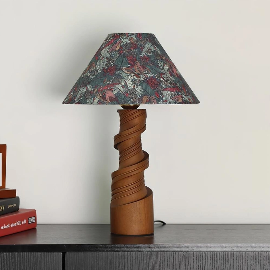 Scrollroot table lamp dark green color variant on dark wood table with patterned shade and book styling