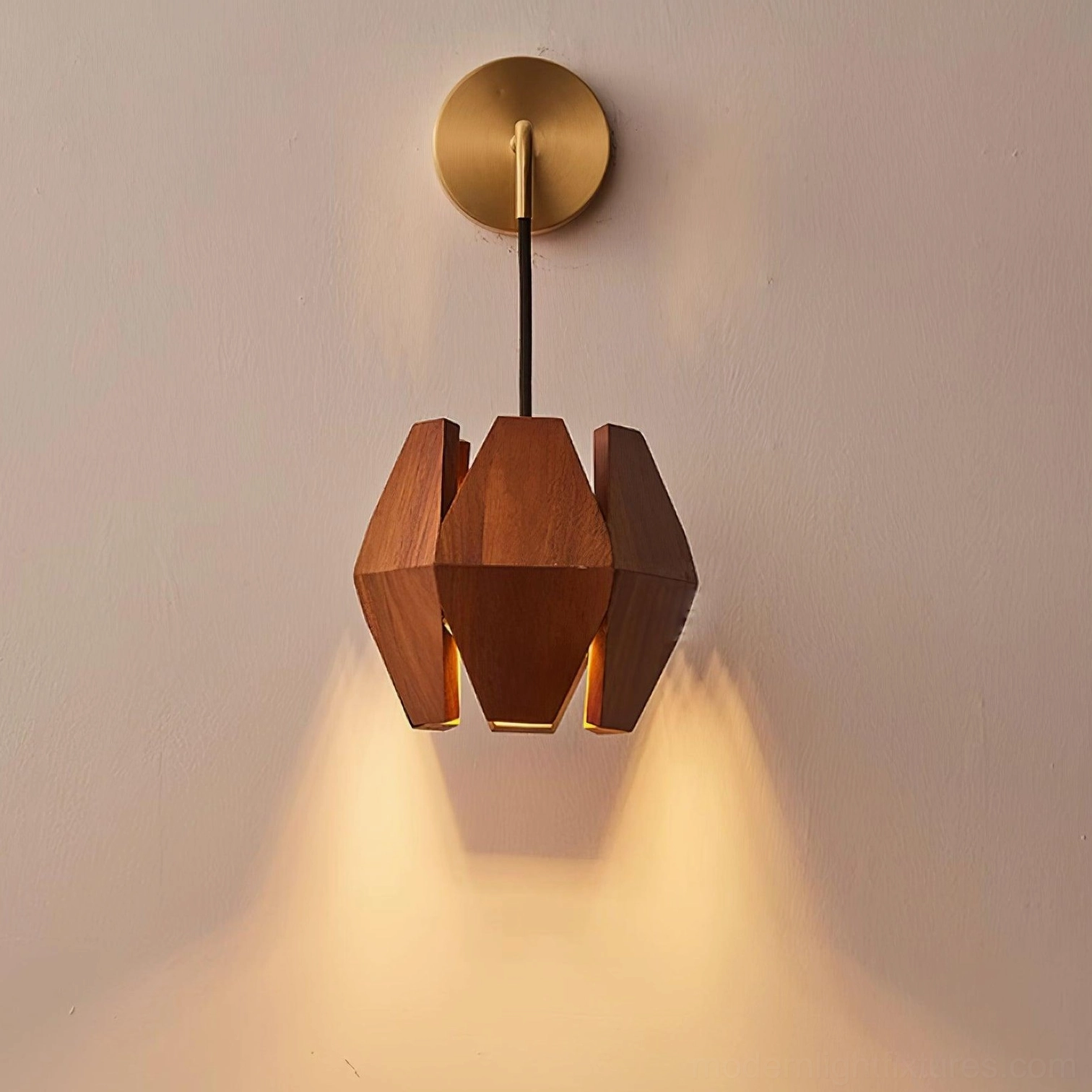 Sculptural wood wall lamp with exposed black cord and brass mount glowing warm light
