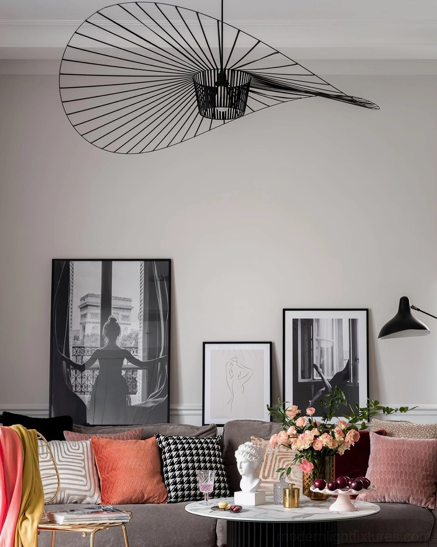 Woven fiber glass pendant lamp suspended above decorated fabric sofa in warm modern living room with Nordic minimalist bohemian styling
