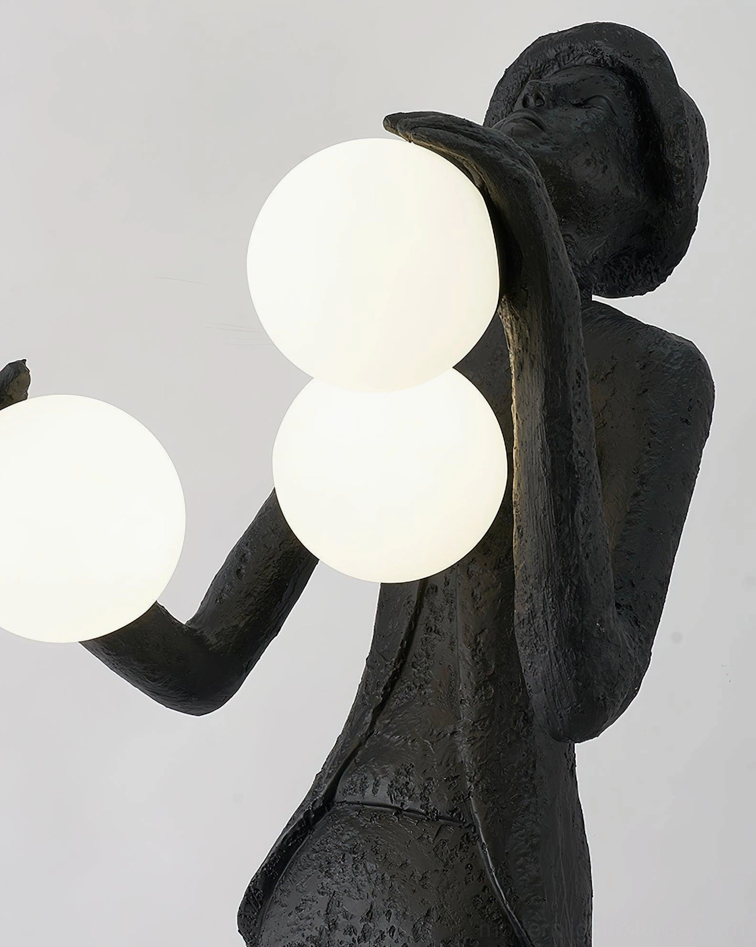 Humanoid sculpture floor lamp frosted glass orbs creating warm ambient light in interior space