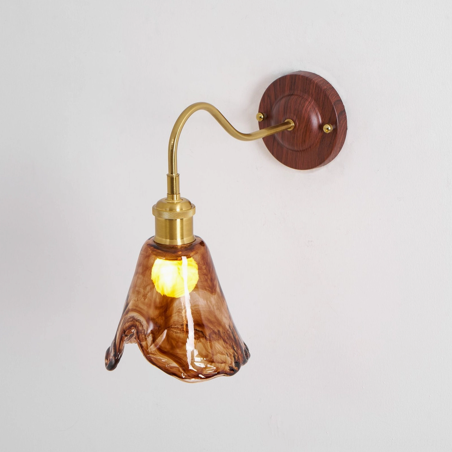 Amber glass wall sconce artistic view highlighting sculptural rippled shade and warm illumination