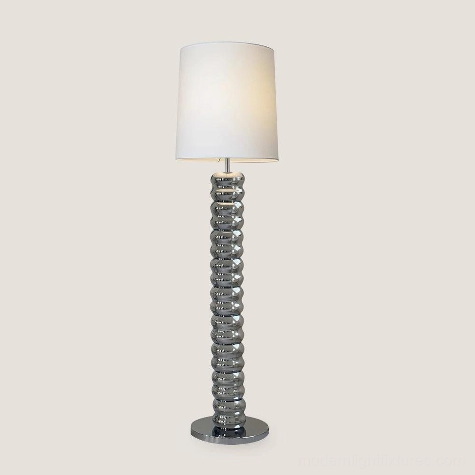 Sculptural stacked wooden rings floor lamp with metal base in minimalist room setting