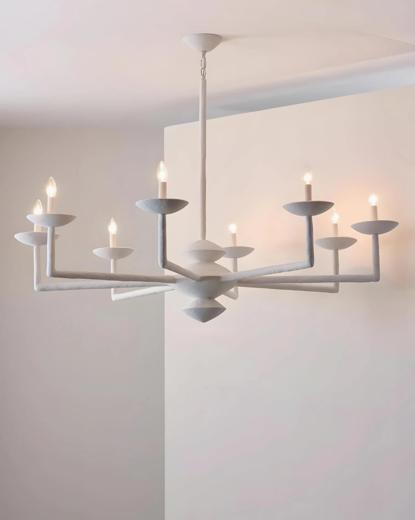 Matte white sculptural candelabra chandelier side low-angle view in minimalist neutral interior