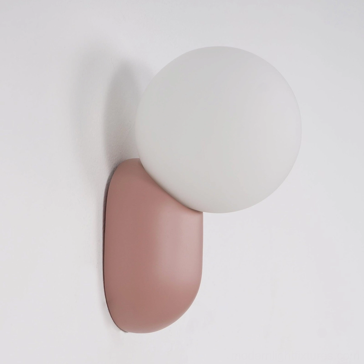 Spherical wall sconce creating dynamic tension between gravity and sculptural form in contemporary art