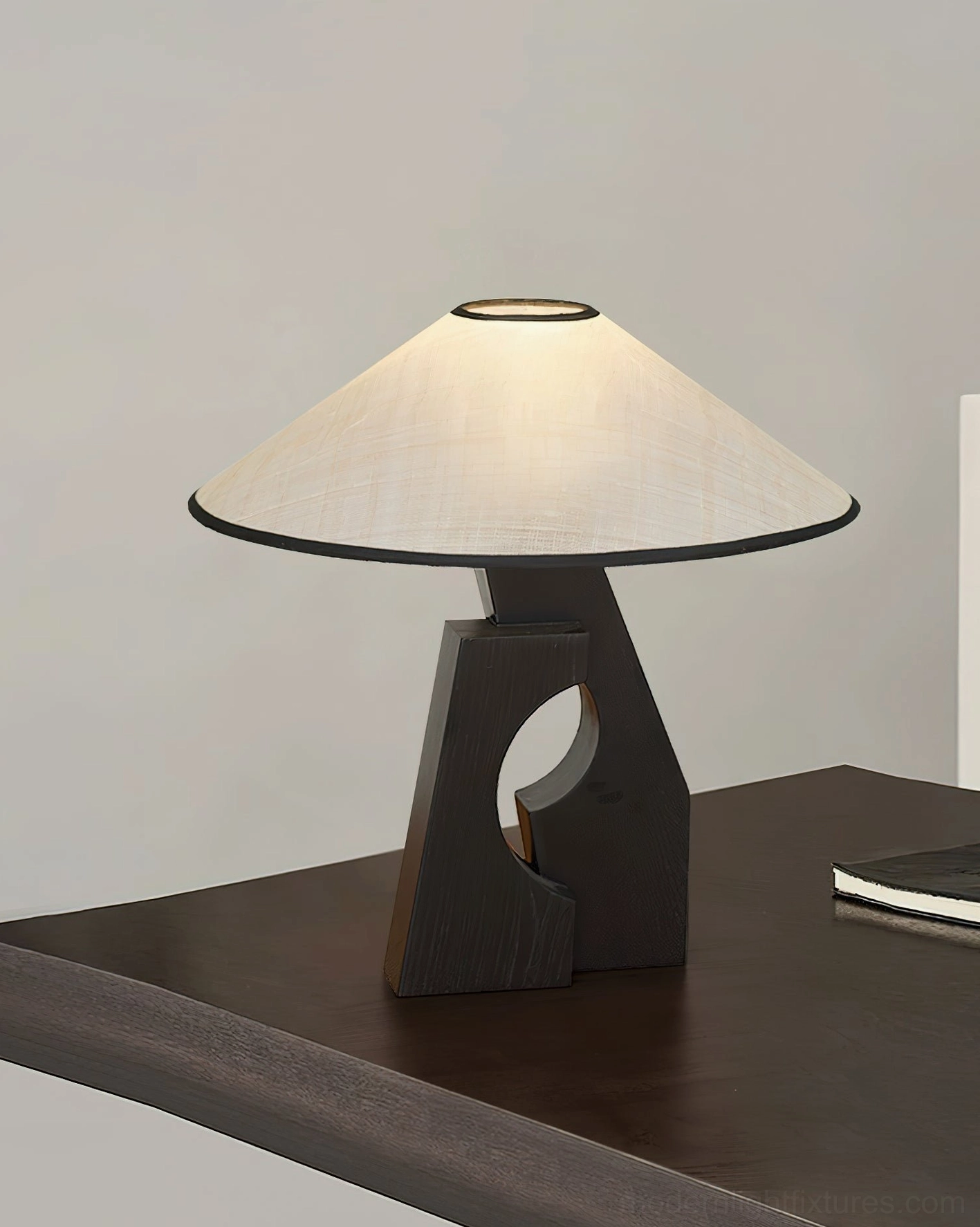 Minimalist wooden base lamp side view on dark wood table with notebook in home office setting