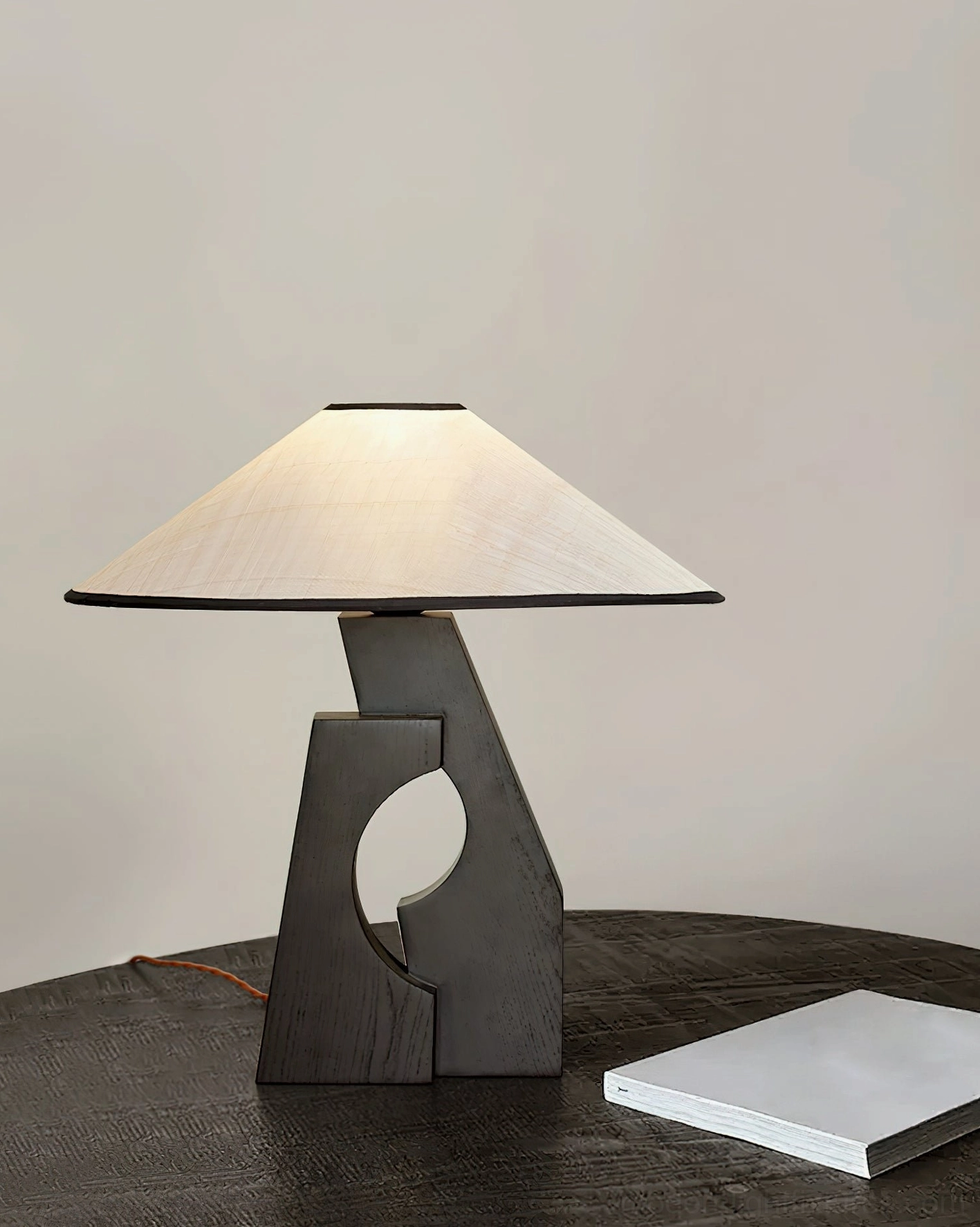 Hand-carved void wood table lamp front view on dark round wooden table studio setting