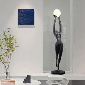 Contemporary female sculpture floor lamp displayed in minimalist living room with wall art and green plant decor