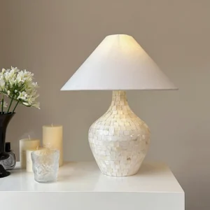 Coastal modern seashell table lamp displayed on white table with flowers and candles - home decor styling