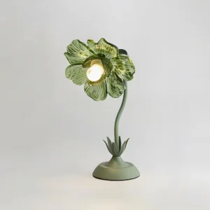 Modern botanical table lamp featuring mint green glass shade and curved metal stem with three-quarter angle view
