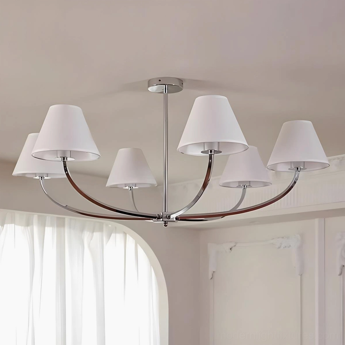 Selmont curved arm chandelier featuring chrome metal frame with white fabric lampshades and warm light output