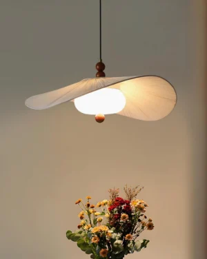 Serafina pendant lamp overhead hanging view with warm ambient glow illuminating pleated shade design, interior home setting with floral decor
