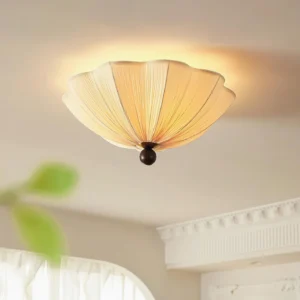 Seralyn modern flush mount ceiling light mounted overhead in French-style residential interior, warm beige pleated shade with dark metal base creating ambient lighting