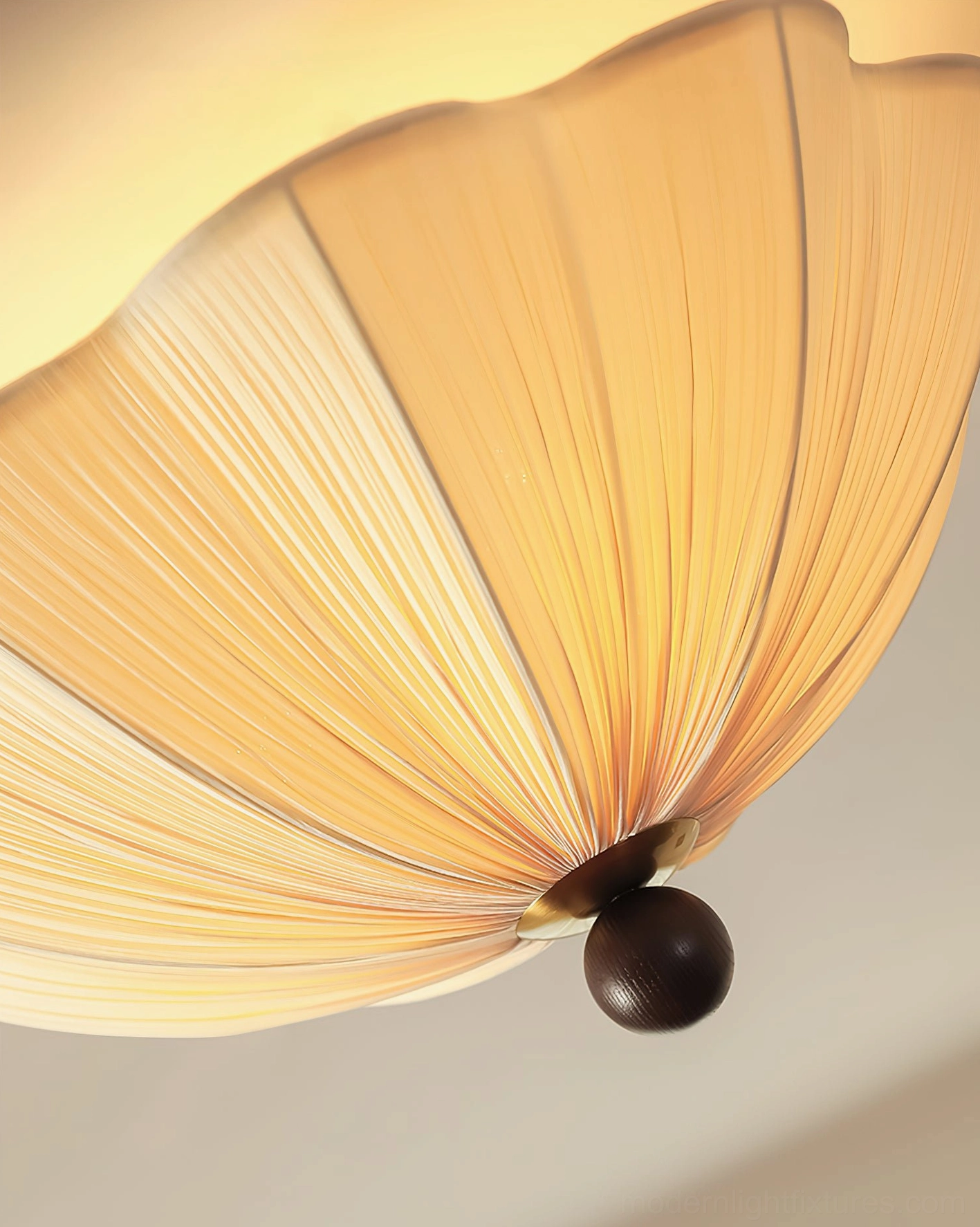 Extreme close-up side view of Seralyn ceiling fixture displaying radial fabric pleats and dark spherical metal base construction detail