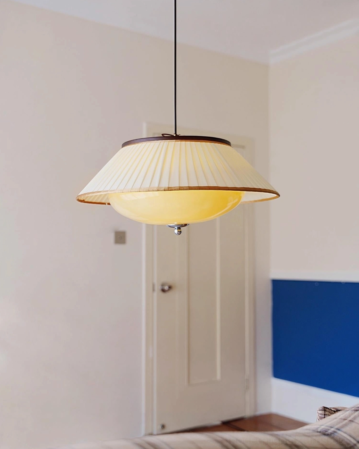 Serenique pendant light in bedroom, warm yellow glow from two-tier shade design