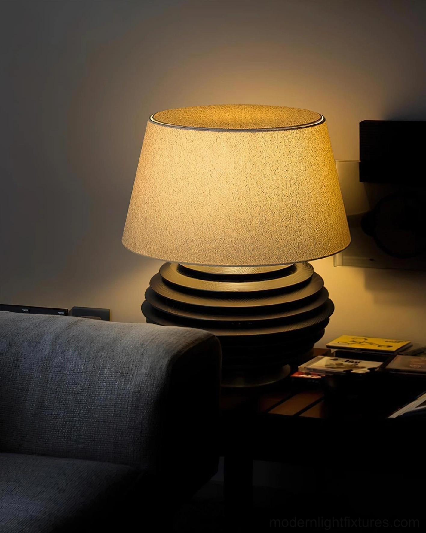 Serenity Strata table lamp with black ribbed base and warm lit beige shade in cozy contemporary living room with side table accessories
