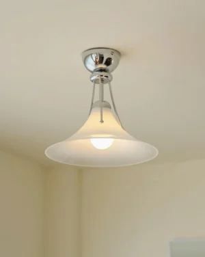 Semi-flush mount ceiling light installed in residential room, low-angle view showing trumpet-shaped white glass shade and chrome suspension