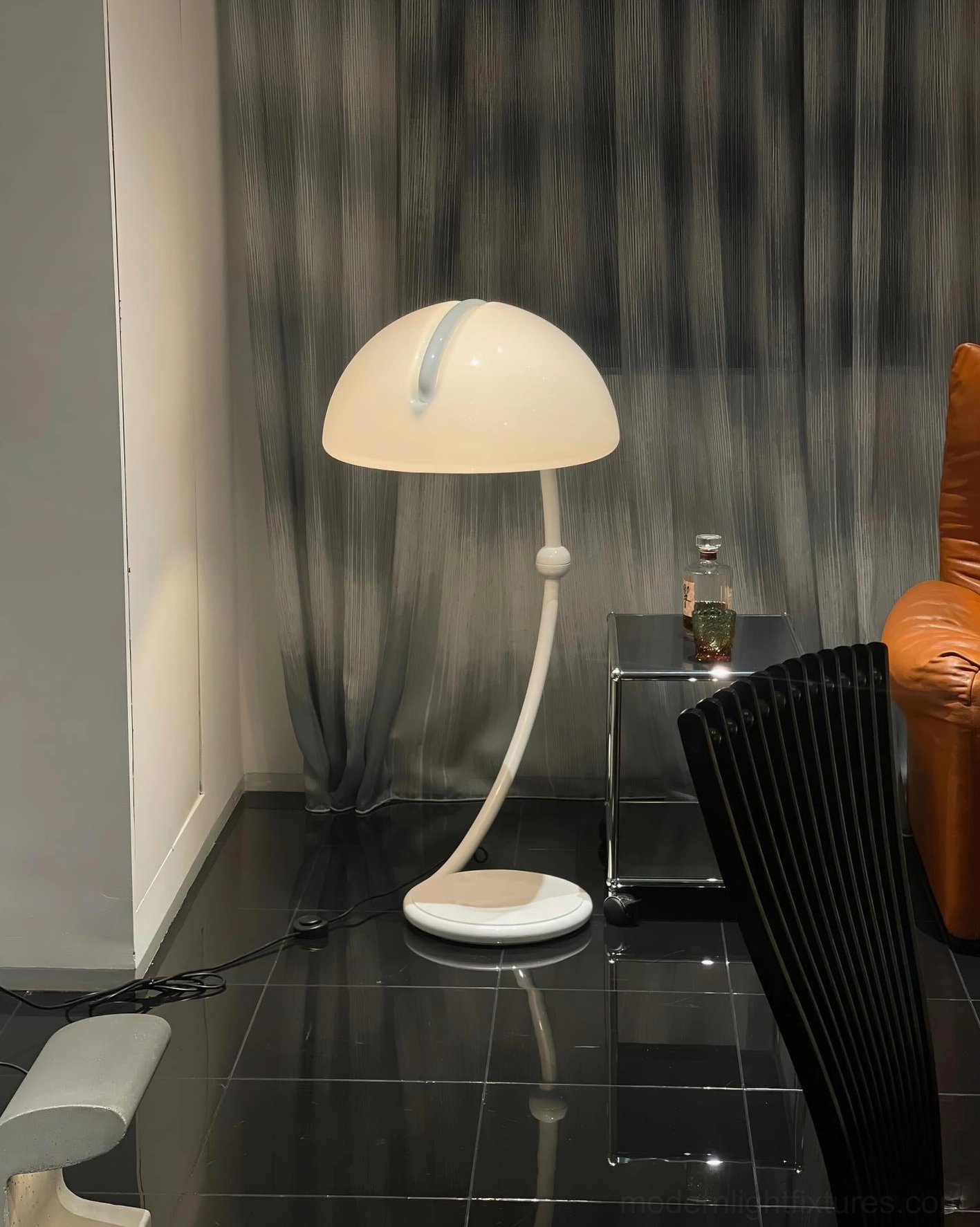 White Serpente dome floor lamp beside small side table in modern dark tile interior