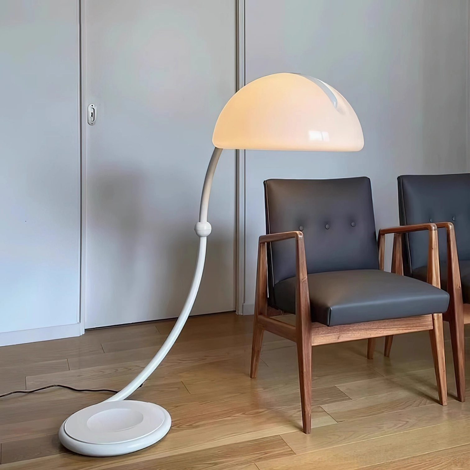White Serpente articulated floor lamp with two wooden armchairs in contemporary wooden-floored interior