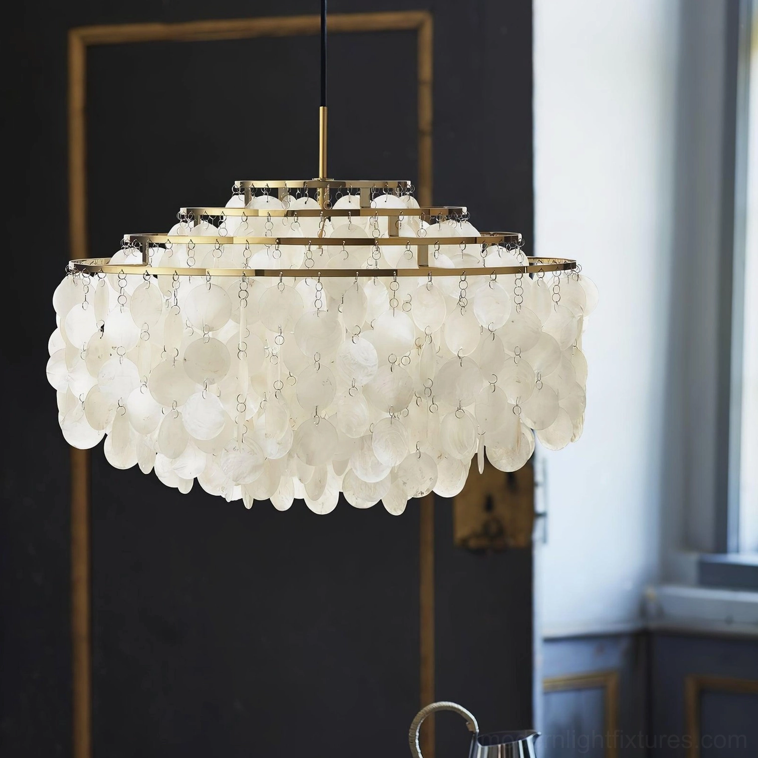 Shell pendant chandelier close-up detail showing layered translucent Capiz discs with brass trim in luxury interior