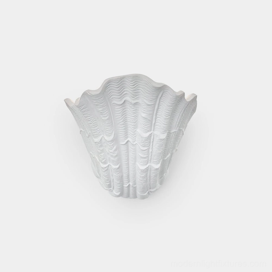 Modern shell plaster wall sconce with embossed ribbed texture, overhead studio view with matte white finish