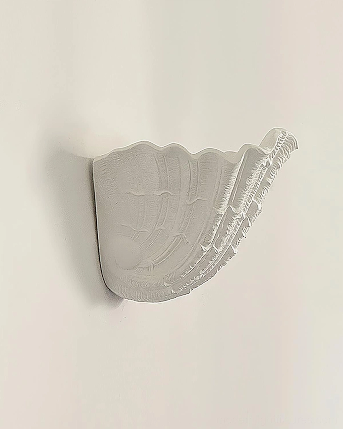 Shell-shaped wall sconce side profile detail showing ribbed texture and off-white plaster finish on plain wall