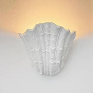 Coastal shell wall lamp mounted indoors with warm ambient backlighting, minimalist Scandinavian interior styling