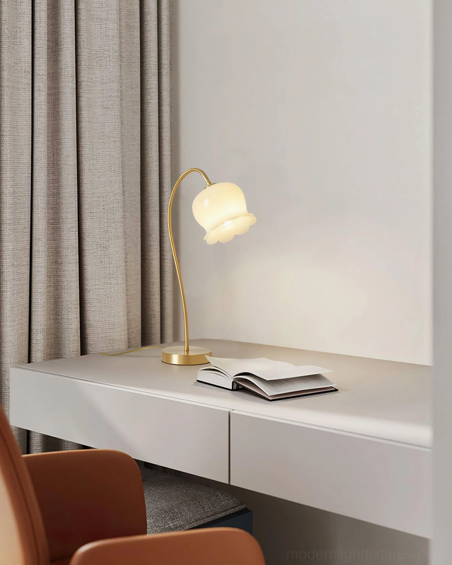 Modern brass table lamp on white desk in home office study area with open book, task lighting setup