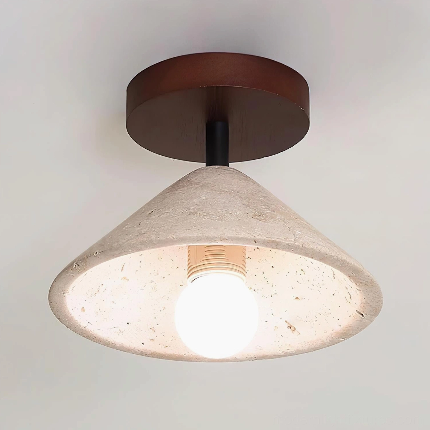 Sierra travertine ceiling light creating warm ambient glow in contemporary minimalist living space