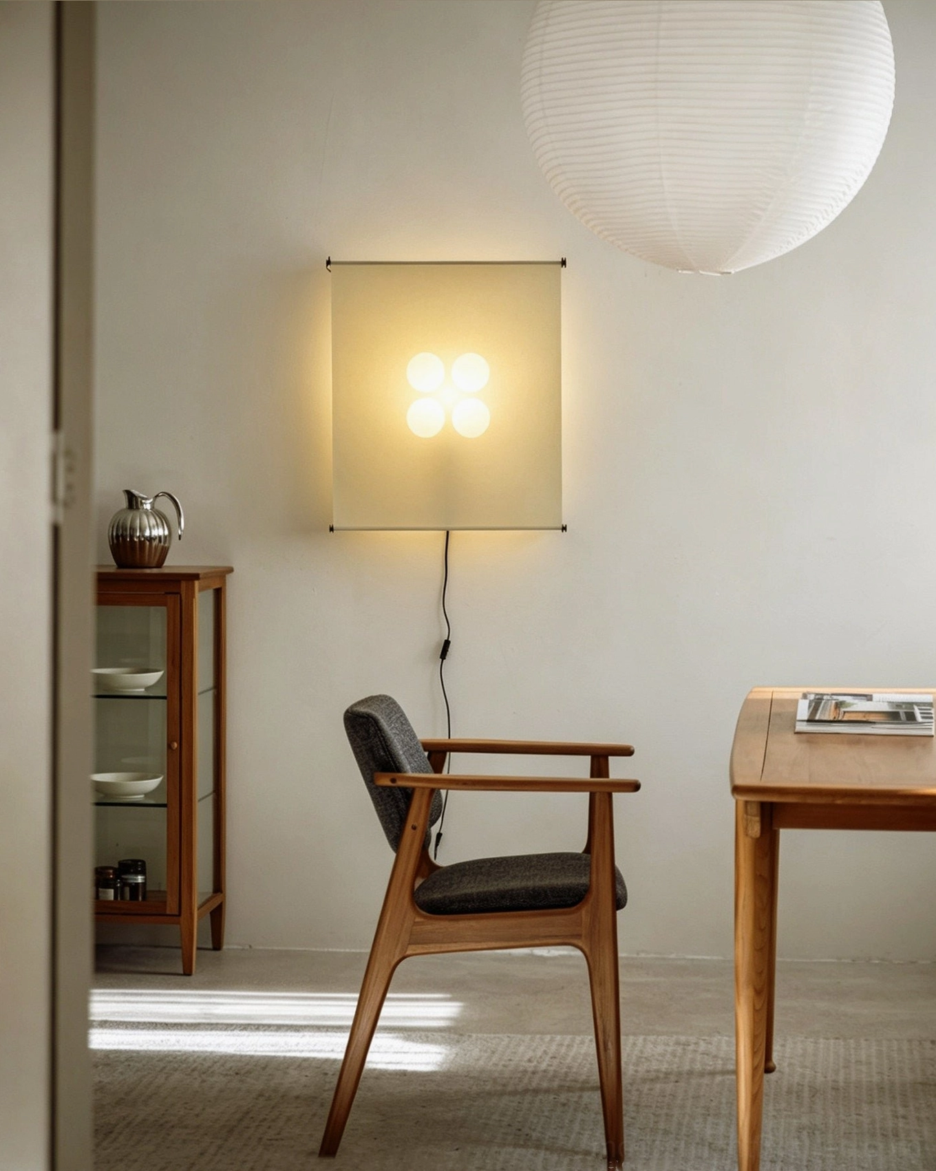 Silque ambient wall sconce in minimalist dining nook with wooden armchair, contemporary architectural paper light design