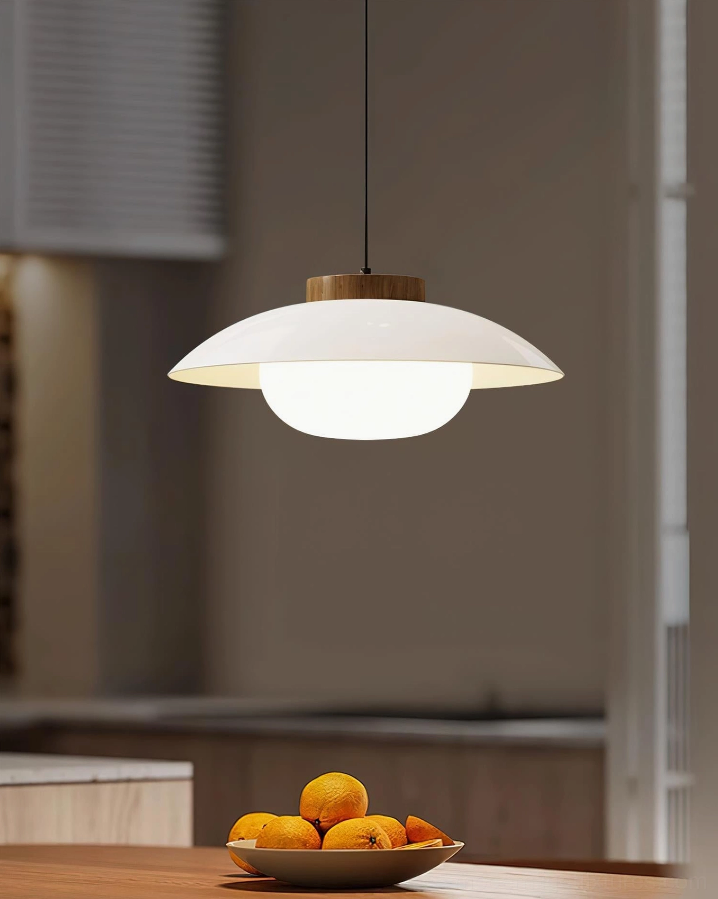 White saucer pendant light with warm wood cap, suspended above kitchen counter in contemporary Nordic dining space