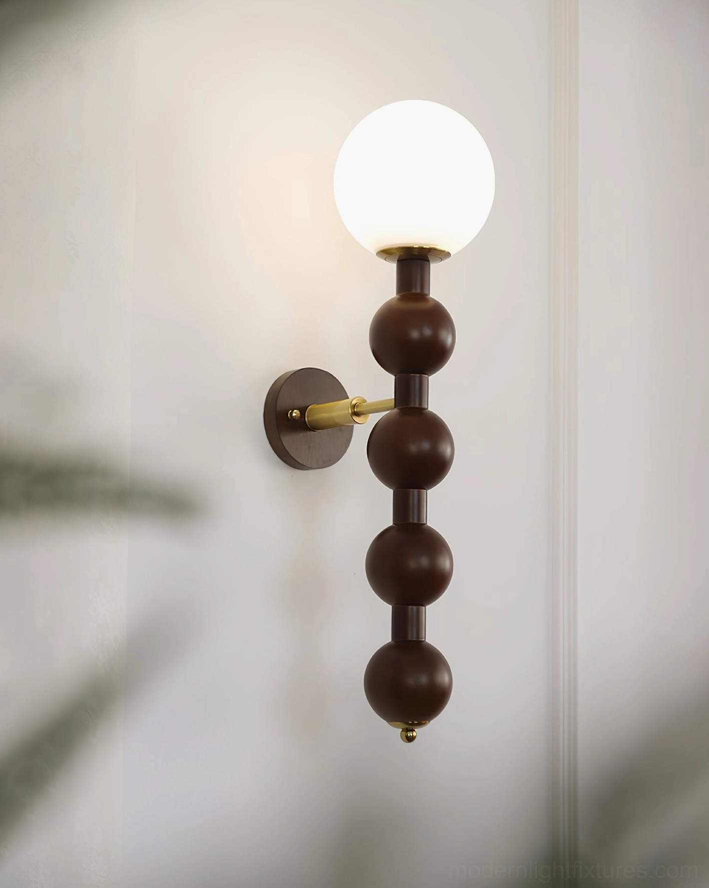 Single beaded globe wall sconce with visible brass mounting bracket on neutral indoor wall