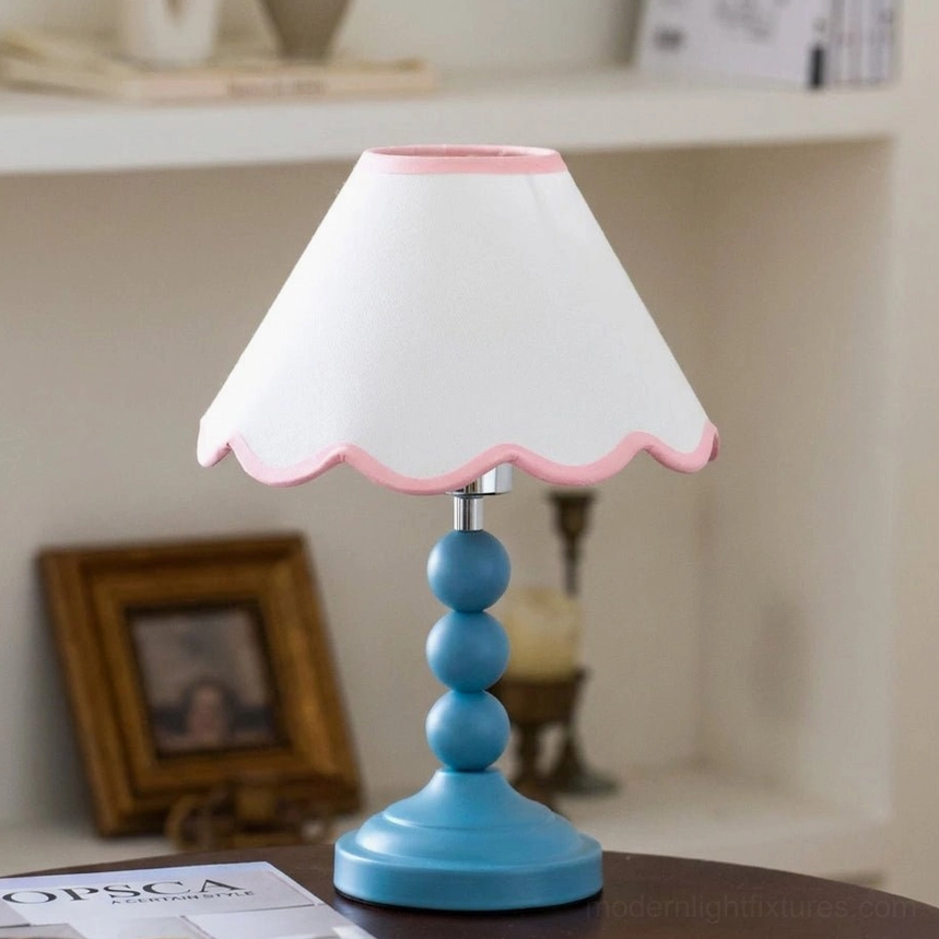 Skylisse table lamp displayed on bedroom nightstand, soft ambient warm light glowing through white scalloped shade