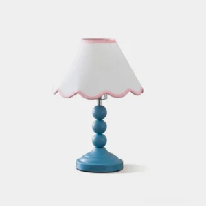 Skylisse table lamp with sky-blue stacked-sphere metal base and white scalloped fabric shade with pink piping, front studio view