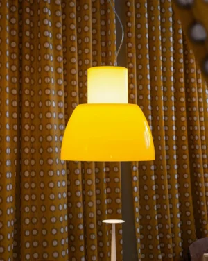 Warm white glass pendant lamp in Scandinavian minimalist living room with yellow polka-dot curtains