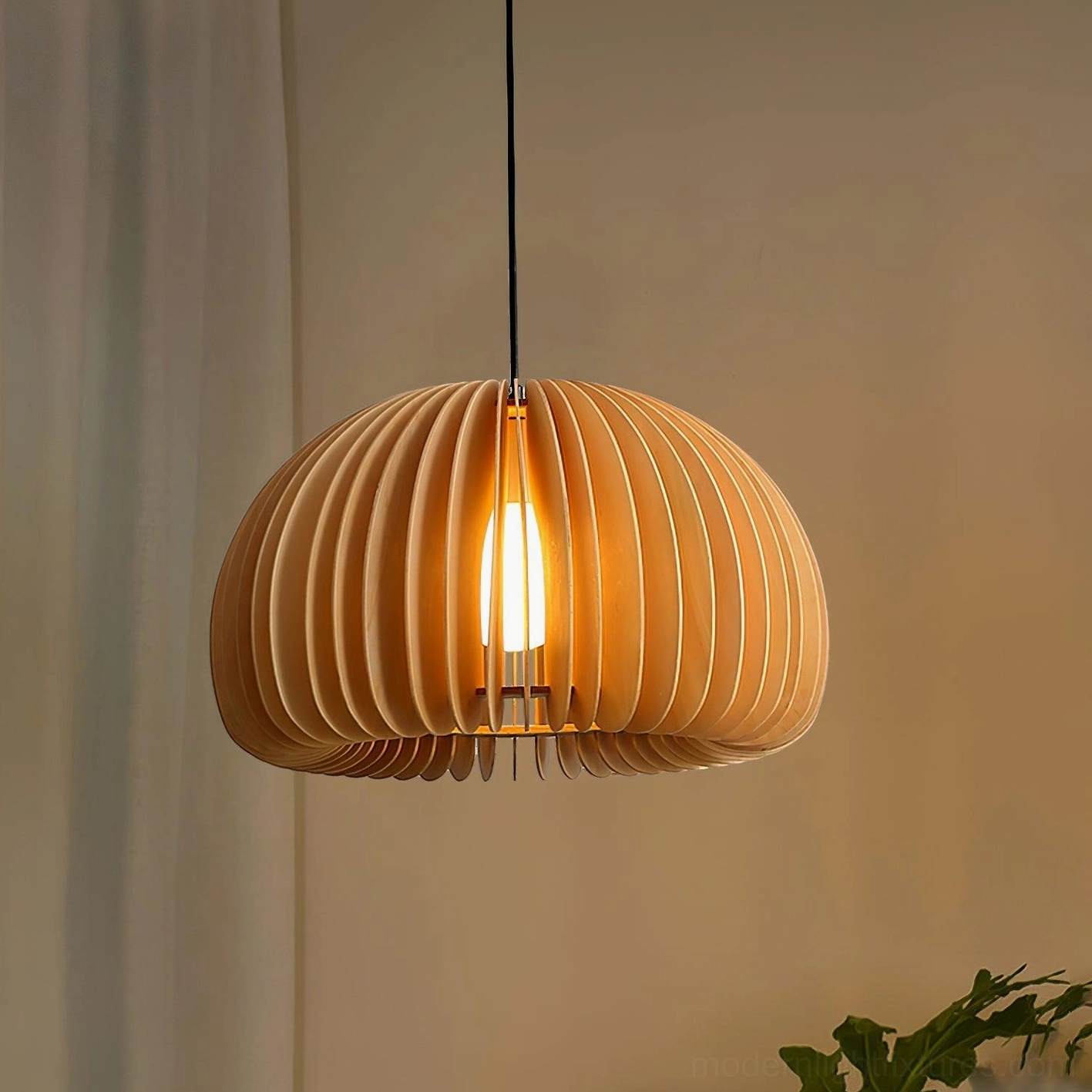 Wood pumpkin pendant light illuminated with warm bulb above dining space with green plants